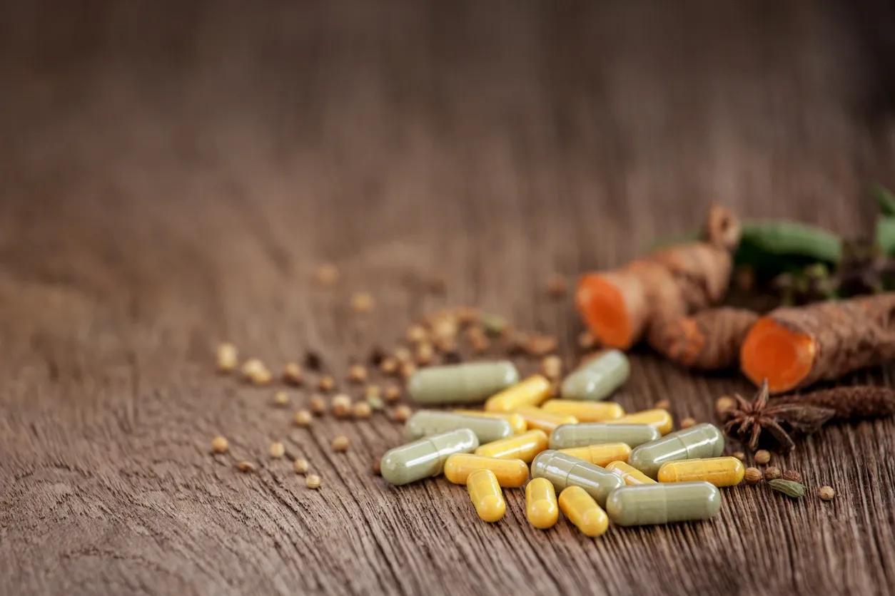 Grey and yellow capsules on dark surface.