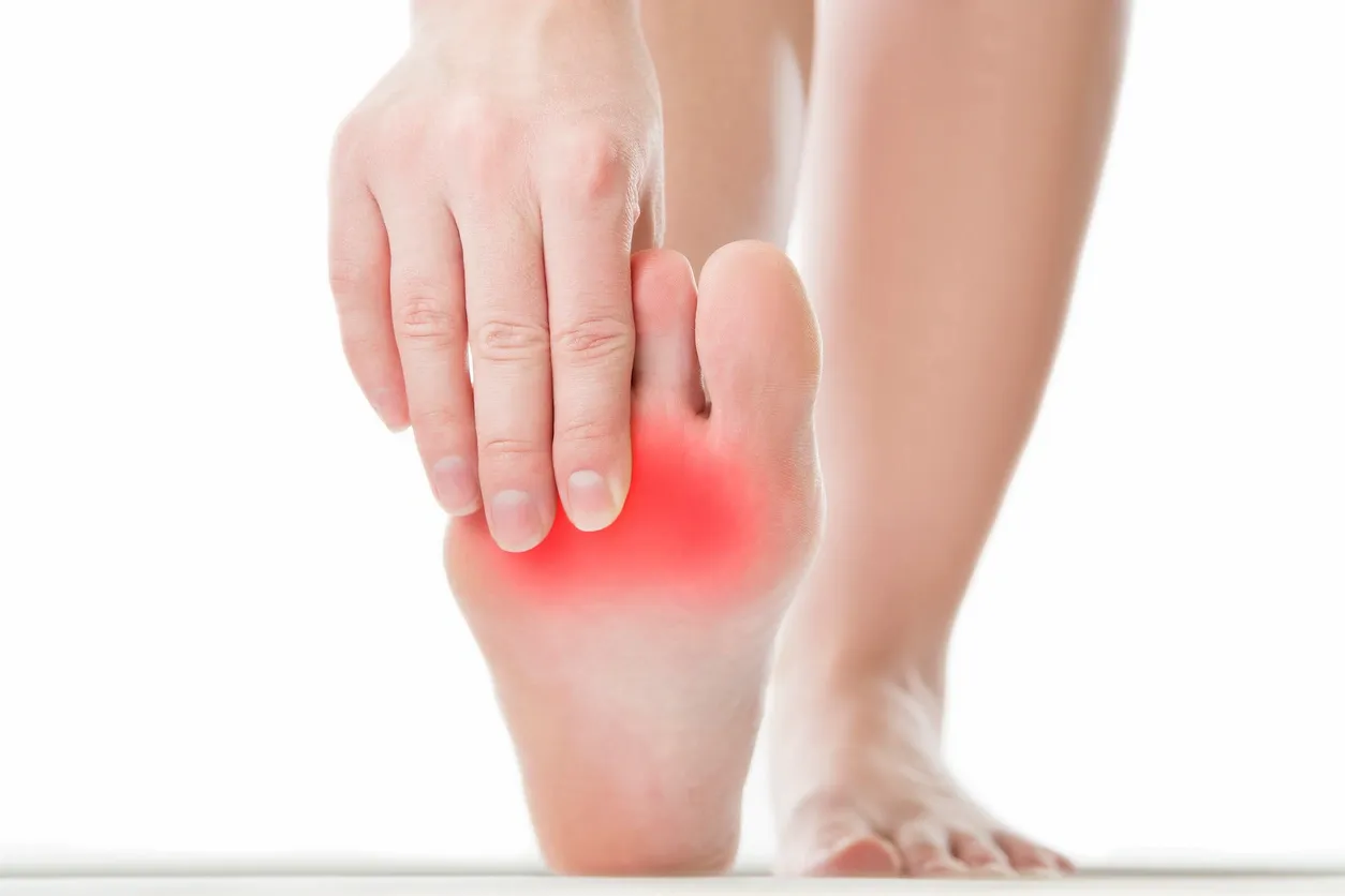 Person touching their foot, with a red glow to signify area of pain.
