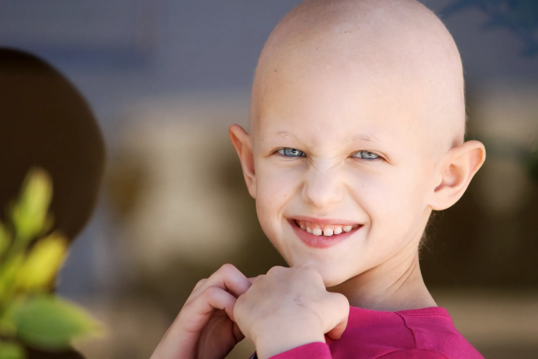Smiling child without hair on their face or head.